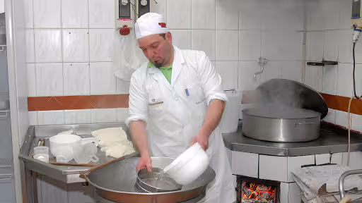 Artisan cheesemaker in Sorrento farmhouse dairy stirring fresh curds during immersive weekend farm tour experience