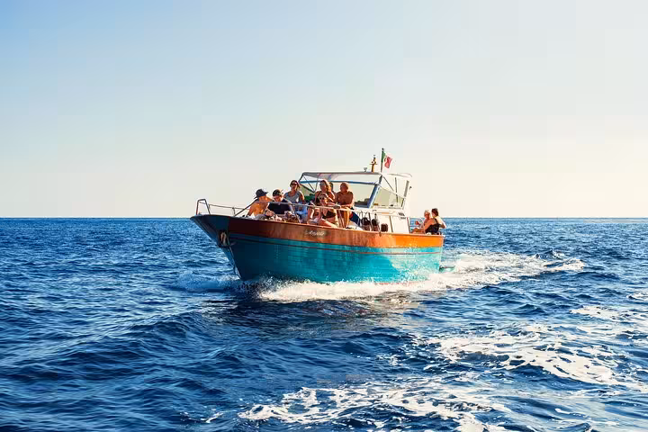 Tourists enjoying a scenic boat ride on the Sorrento Coast during a sunny day, perfect for a sunset sail adventure.