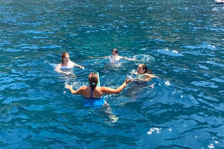 Group of friends swimming in the clear blue waters of the Sorrento Coast, enjoying a refreshing dip during the sail.