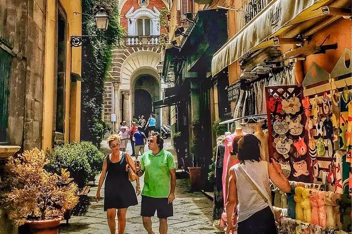 Tourists strolling through Sorrento's charming streets lined with colorful shops during a guided walking tour.