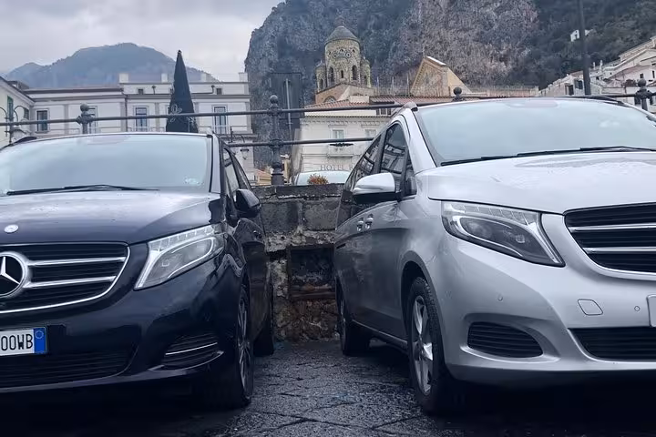 Luxury vans parked near historic architecture, perfect for Sorrento to Naples private transfer service.