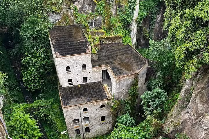 Historic stone mill surrounded by lush greenery in Sorrento, a highlight of the guided walking tour experience.