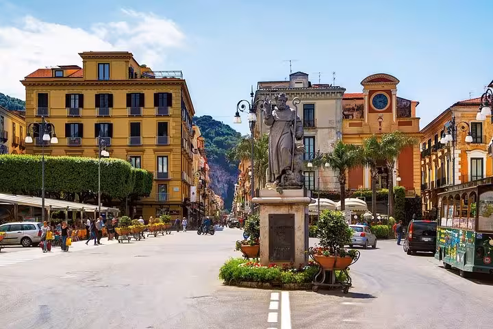Charming street scene in Sorrento with historic architecture and a statue, a highlight on the 10-hour Grand Tour.