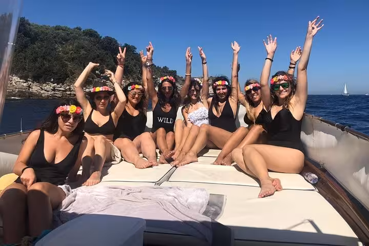 Group of friends celebrating with flower crowns on a boat during Sorrento Coast sunset sail.