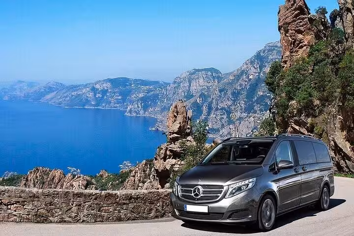 Scenic coastal drive with private transfer van, showcasing stunning views from Sorrento to Rome journey.