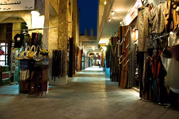 Illuminated alleyway at Souq Waqif featuring traditional garments and accessories in Doha's bustling night market.