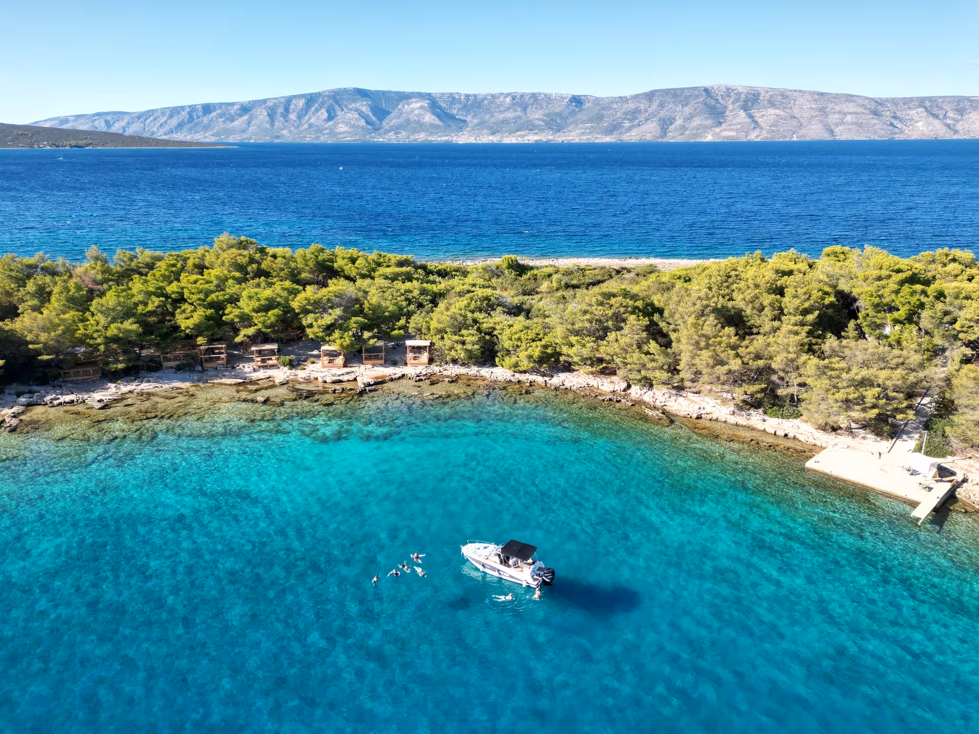 Aerial of speedboat and swimmers in crystal-clear Blue Lagoon, 3 Islands Hidden Cave tour stop