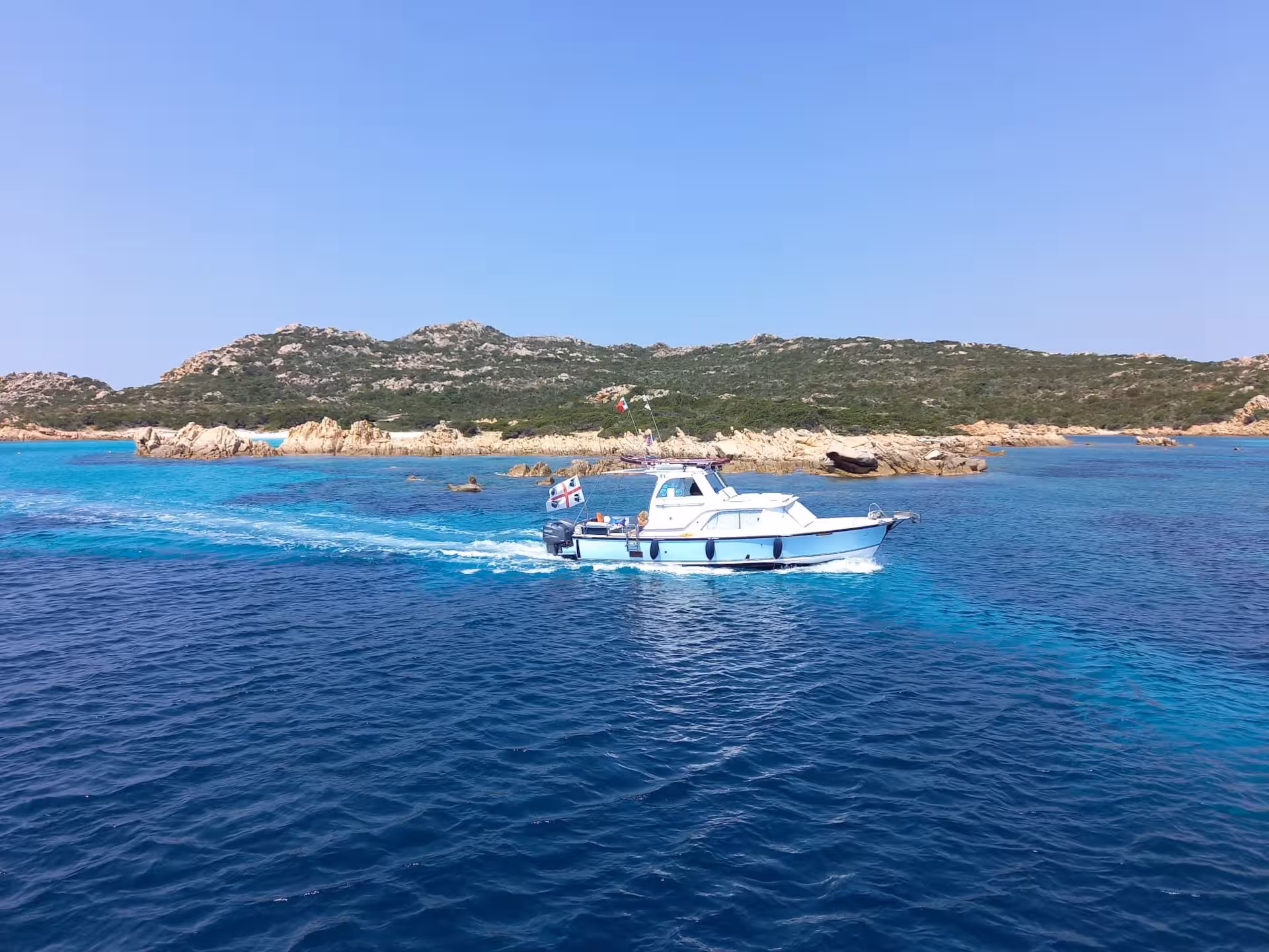 Speedboat cruising through the turquoise waters of La Maddalena Archipelago near Palau, surrounded by rocky landscapes.