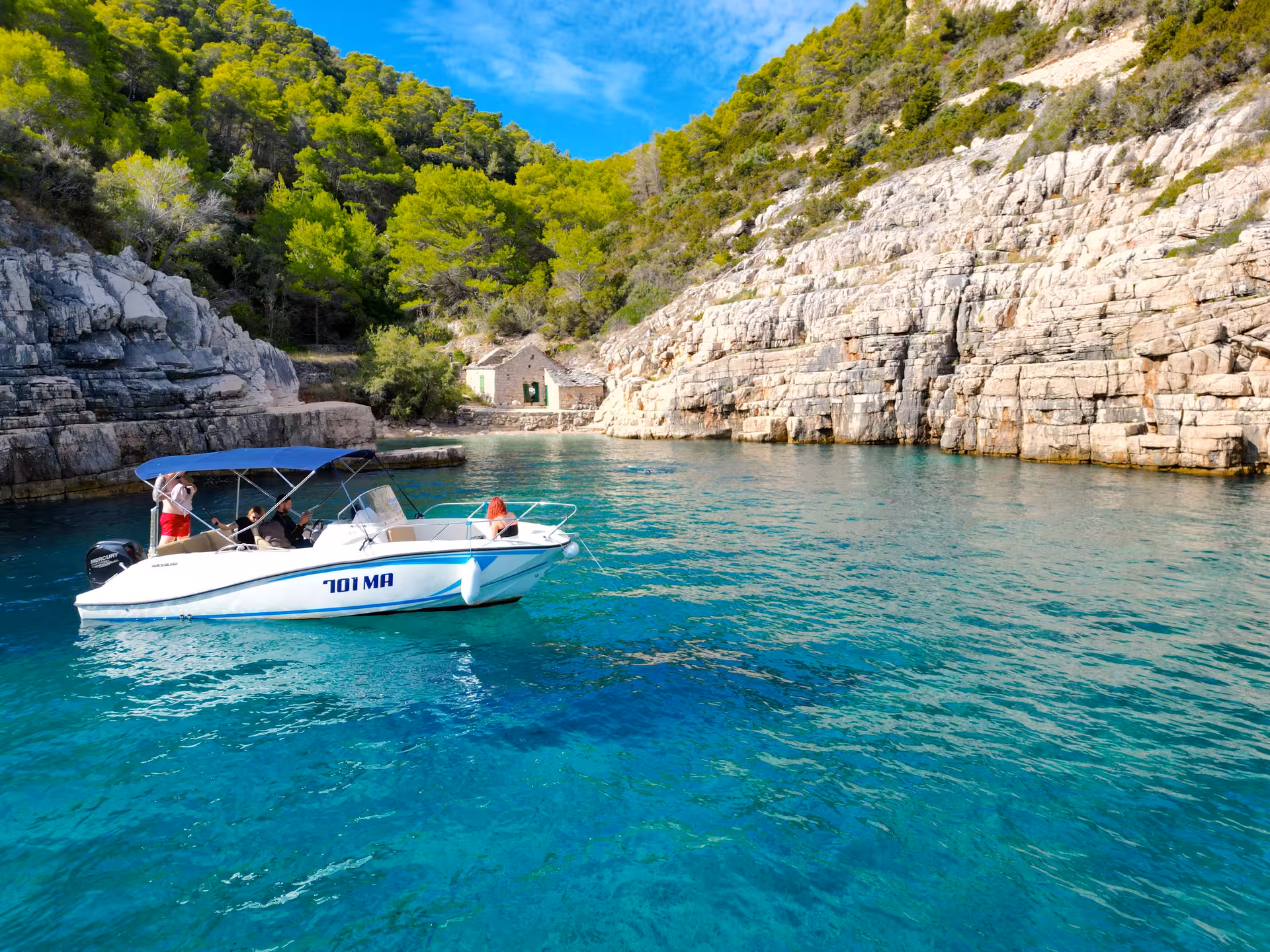Speedboat in turquoise bay by rocky cliffs, stop on 3 Islands Hidden Cave & Blue Lagoon tour