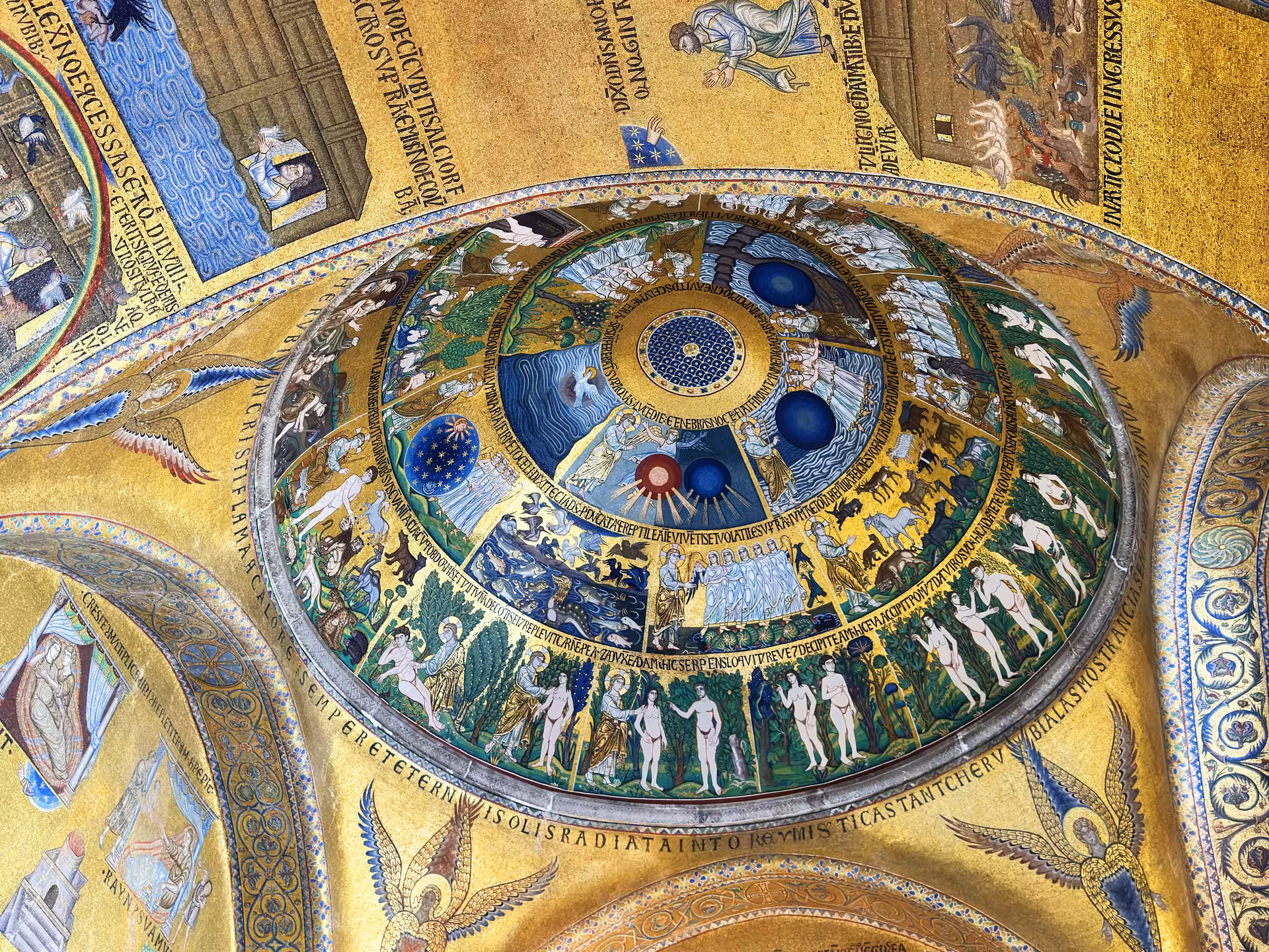 Intricate mosaic ceiling inside St. Mark's Basilica depicting biblical scenes with gold and vibrant colors.