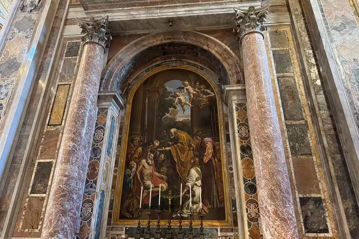 Vibrant religious painting framed by ornate marble columns in St Peter's Basilica, Vatican.