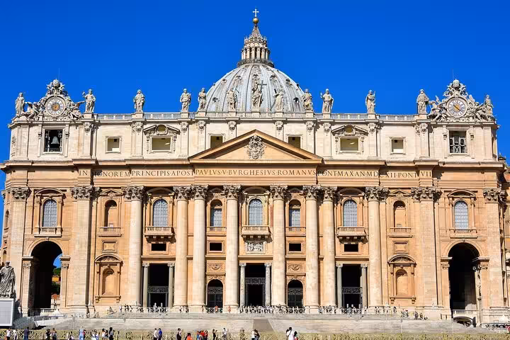 St. Peter's Basilica facade under clear blue skies, highlighting the grandeur of Vatican architecture in Rome tour.
