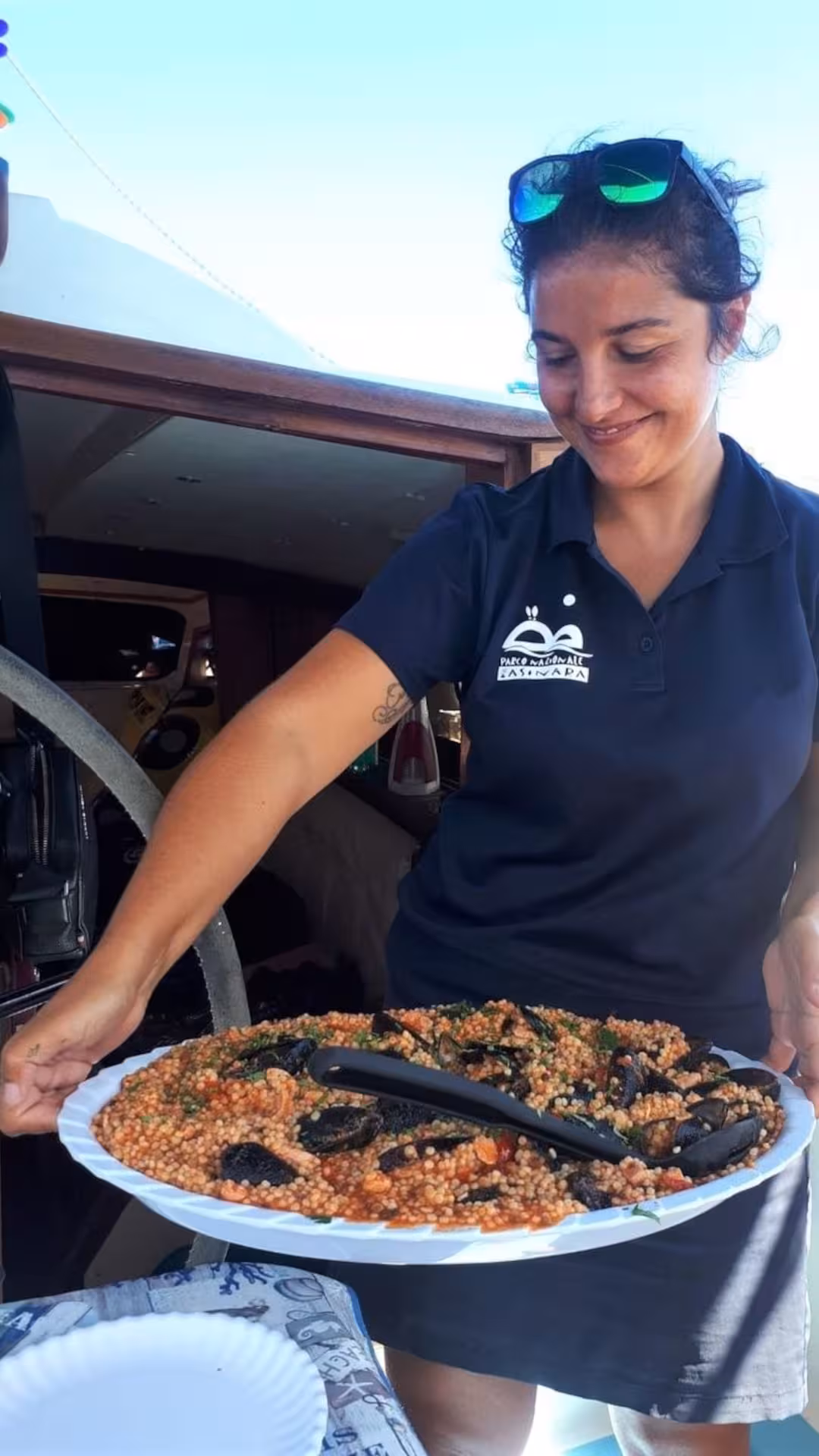 Crew member serving delicious seafood couscous on a catamaran during the Gulf of Asinara tour from Stintino.