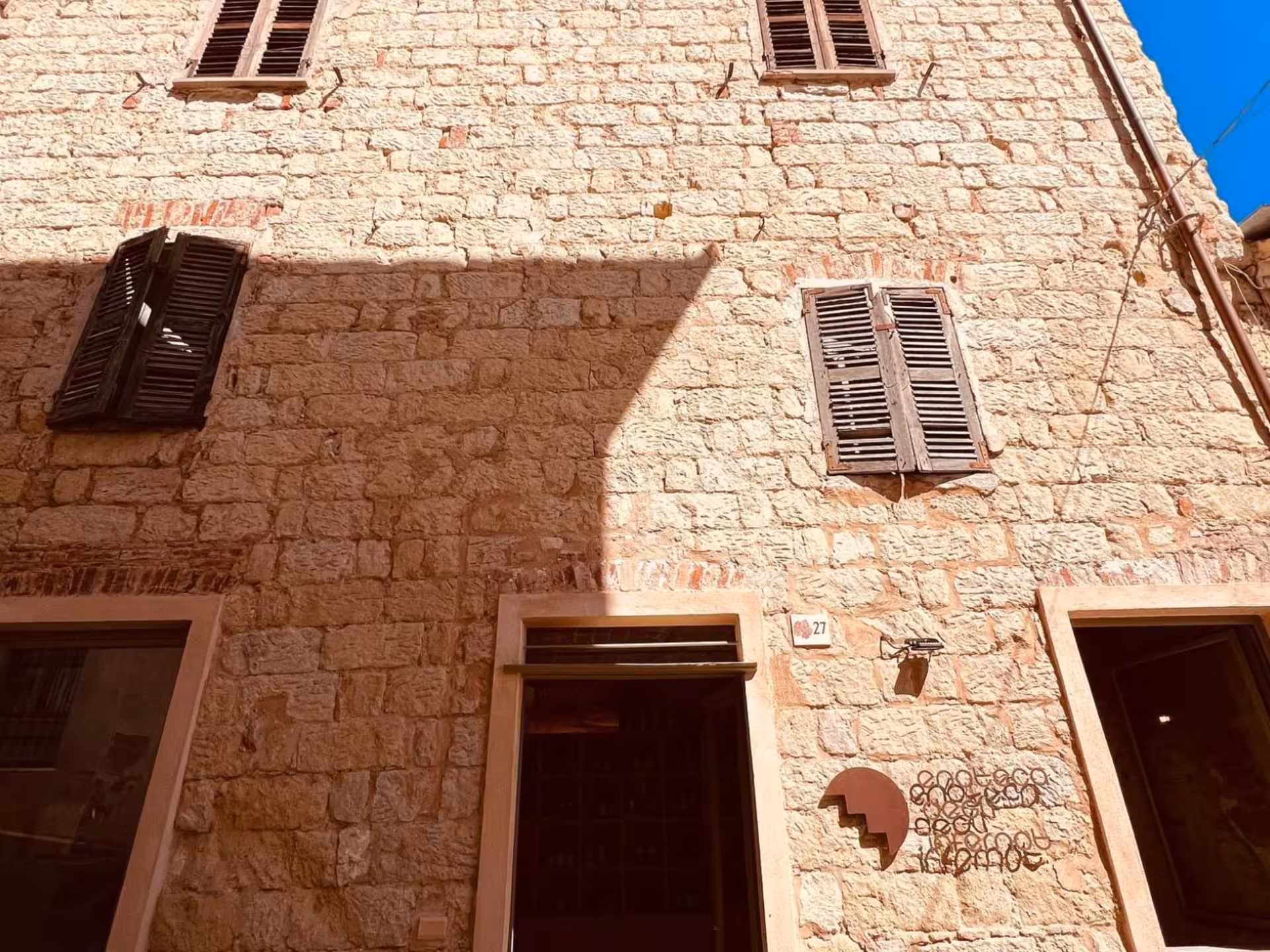 Charming stone building with rustic shutters in Asti, ideal for exploring Italian architecture and local culture.