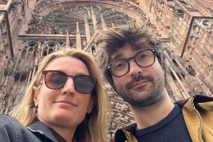 Two travelers selfie beneath Strasbourg Cathedral facade on interactive scavenger hunt and walking tour