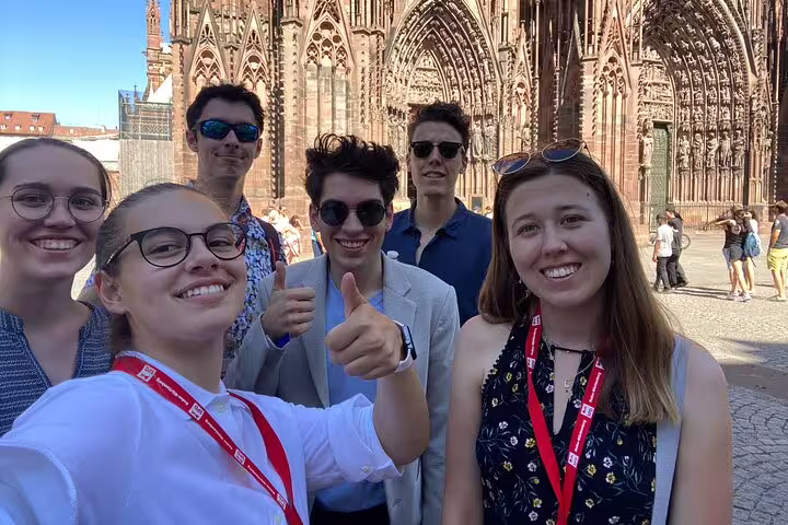 Friends on Strasbourg scavenger hunt walking tour posing by Strasbourg Cathedral, city highlights selfie