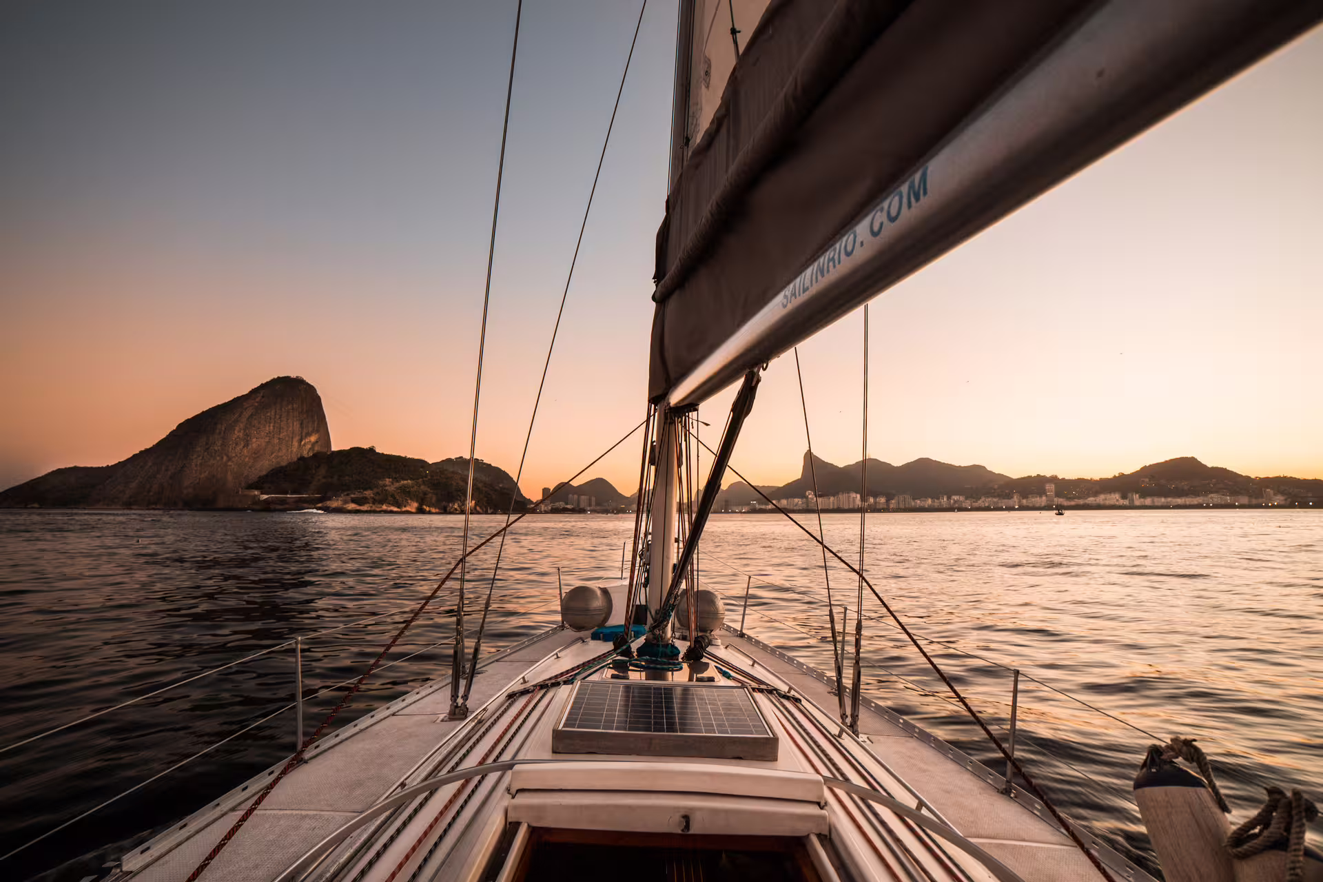 Breathtaking view of Sugarloaf Mountain from a sailboat at sunset, capturing Rio's iconic skyline and tranquil waters.