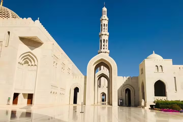 Stunning architecture of Sultan Qaboos Grand Mosque under clear blue skies, a highlight of the Oman private tour package.
