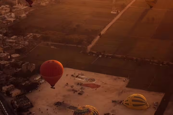 Sunrise Luxor hot air balloon launch site over farmland, pre-flight setup for ride with hotel transfer