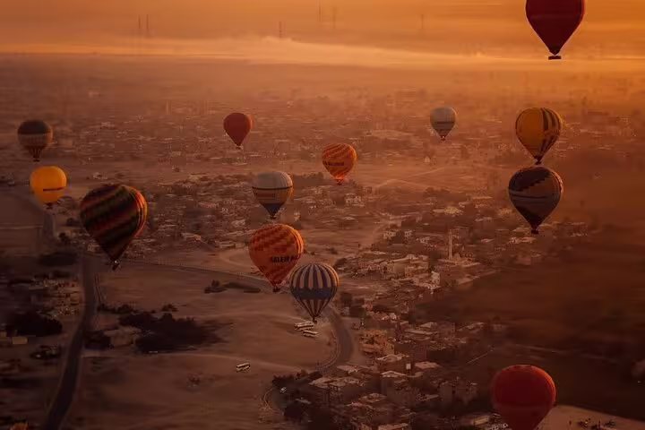 Sunrise hot air balloon ride over Luxor with multiple balloons floating above the Nile Valley, Egypt