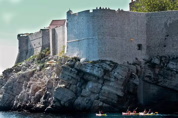 Guided sea kayaking below Dubrovnik city walls, ideal sunset kayaking and snorkeling tour with water and wine
