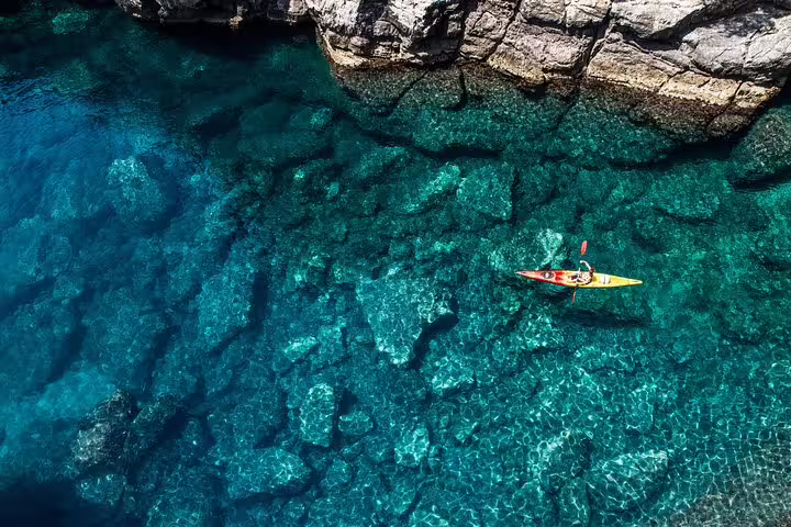 Aerial view of sea kayak over crystal-clear turquoise water, ideal for sunset kayaking and snorkeling with wine