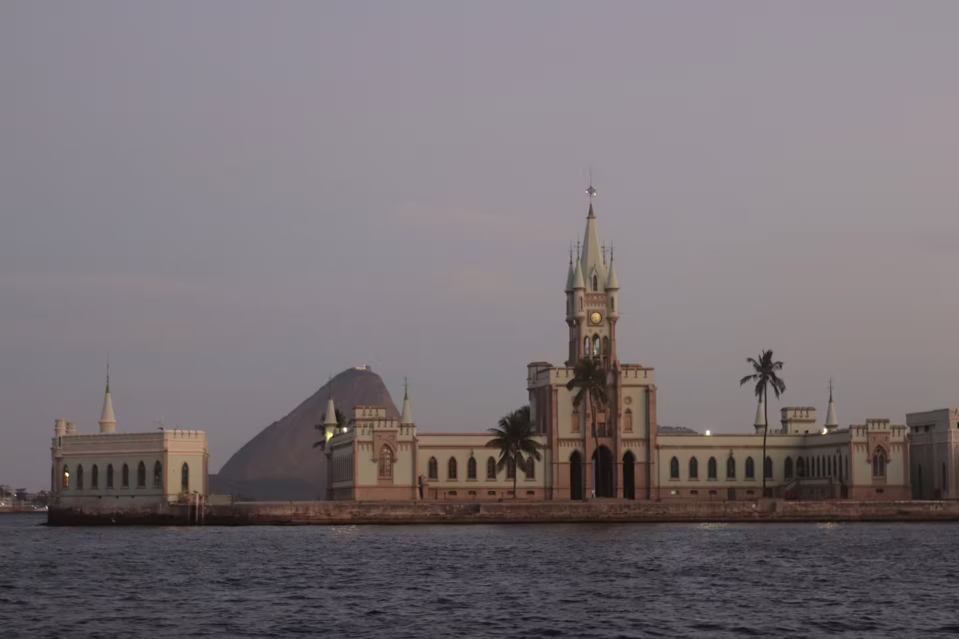 Historic Ilha Fiscal castle silhouetted against a tranquil Rio de Janeiro sunset sky.