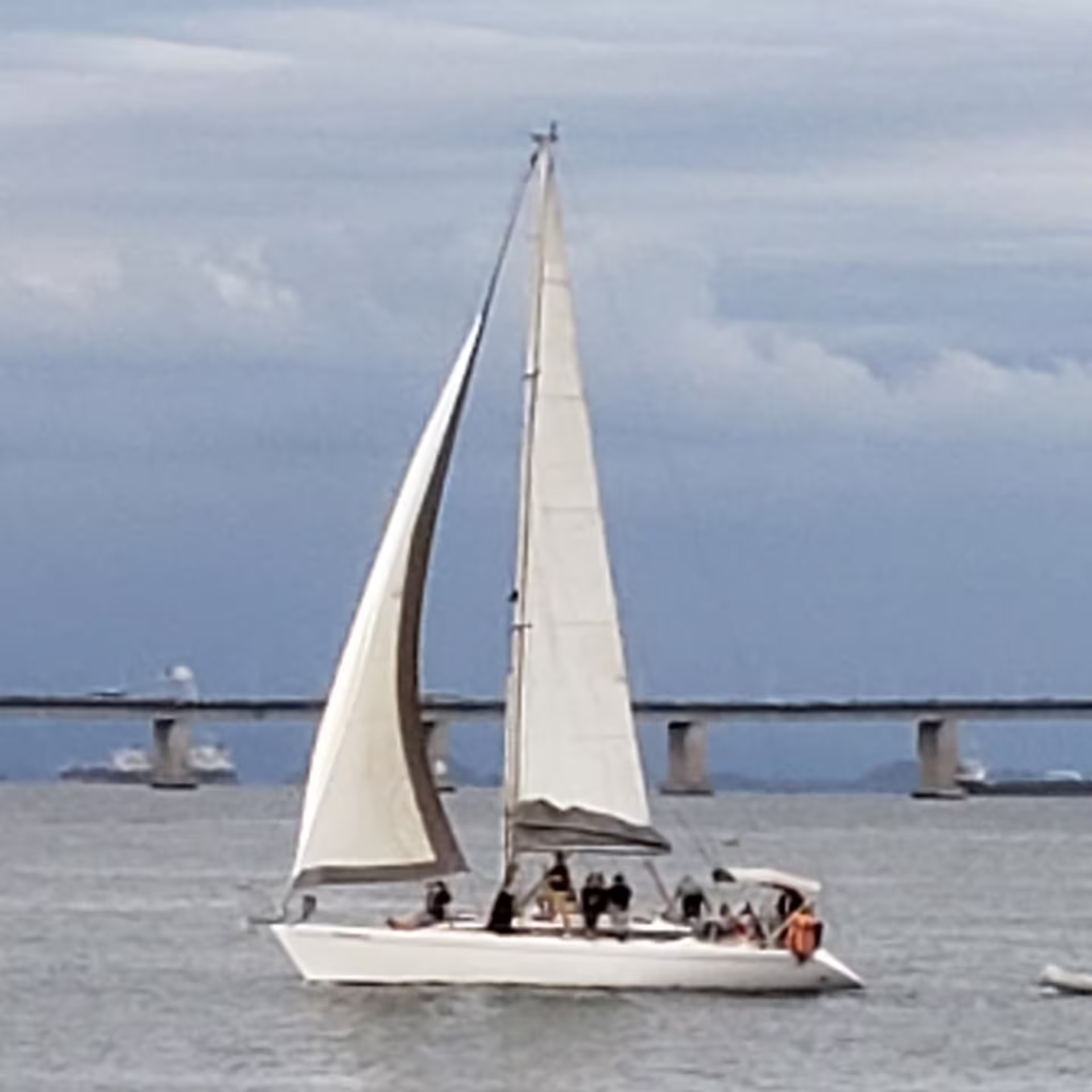 Sailboat gliding under Rio's iconic bridge during a picturesque sunset cruise tour.
