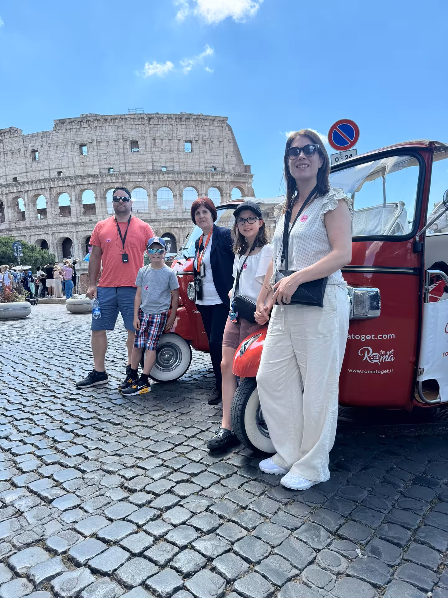 Family poses by a tuk-tuk near Colosseum, a highlight of the Sunset in Rome Combo Tour.