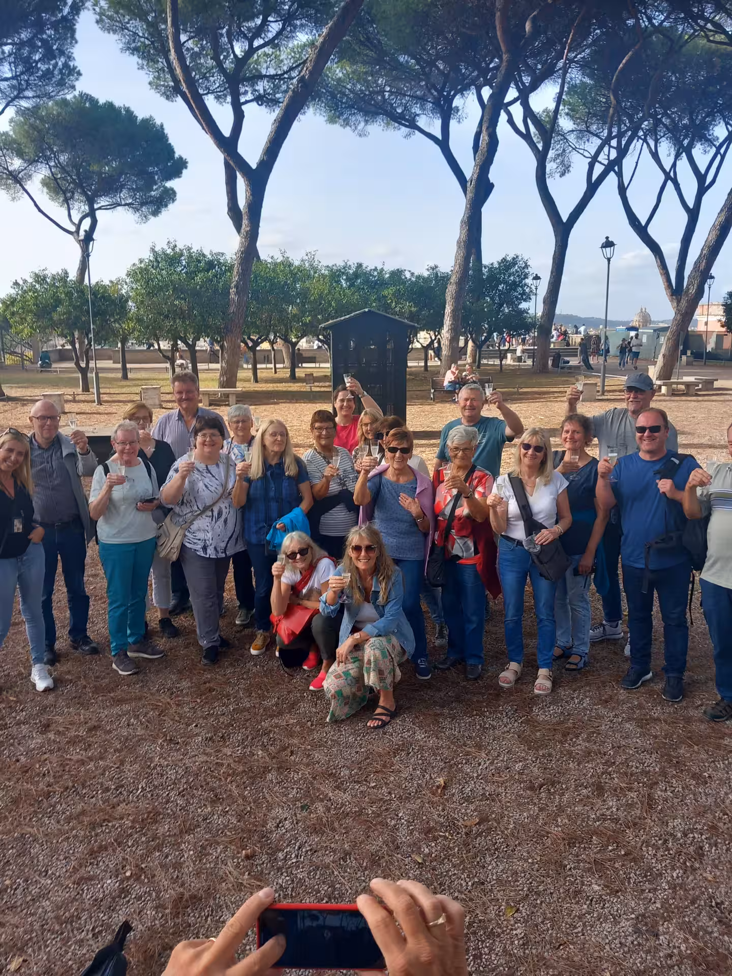 A large group of tourists gather for a memorable photo under the trees during the Sunset in Rome Combo Tour.