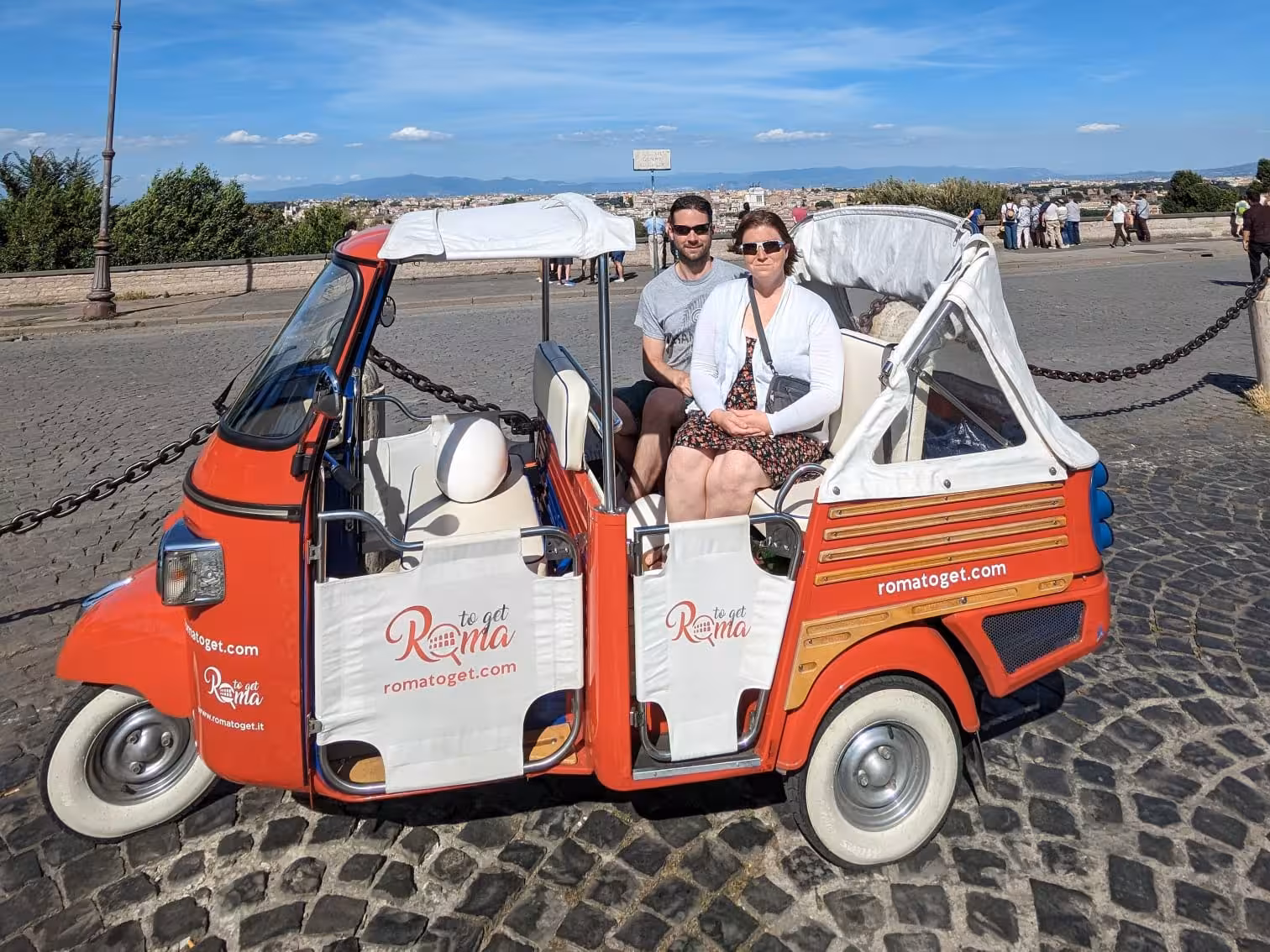 Tourists seated in a tuk-tuk with panoramic views of Rome on the Sunset Combo Tour.