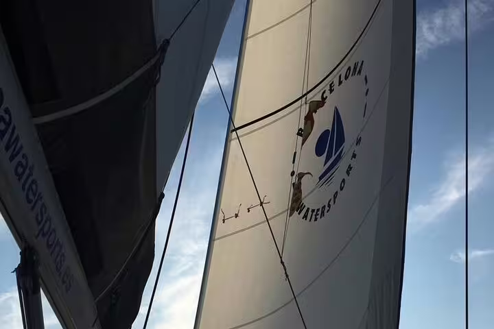 Sailing boat with open sails set against a vibrant sunset sky, showcasing the “2 Hour Sunset Sailing Experience” in Barcelona.