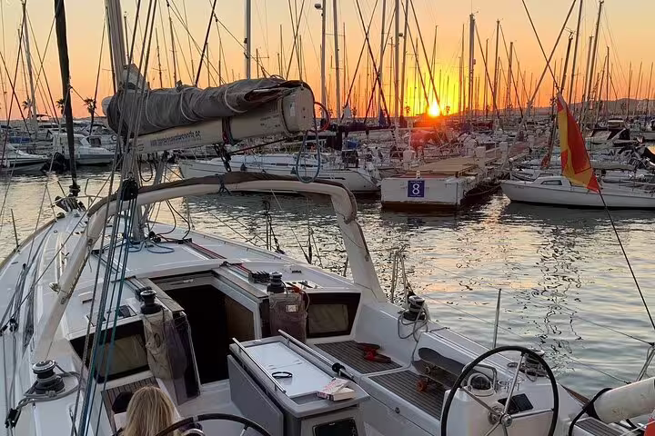 Sailboat docked at sunset with open bar and tapas, perfect for a 2-hour sunset sailing experience in a picturesque marina.
