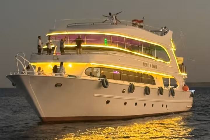 Sunset yacht for Sharm evening Oriental dinner cruise, warm deck lights on the Red Sea before belly dance show