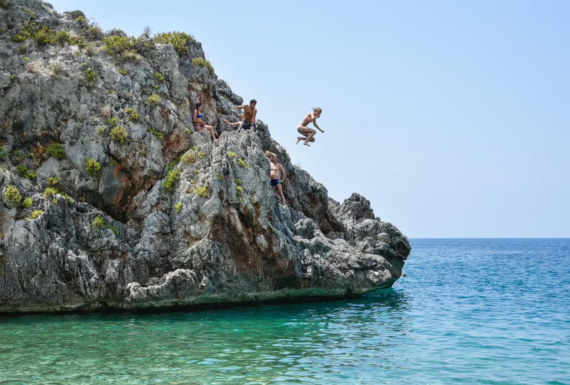 Cliff jumping into crystal-clear sea near Kardamyli on a stand up paddleboarding tour in Mani, Greece