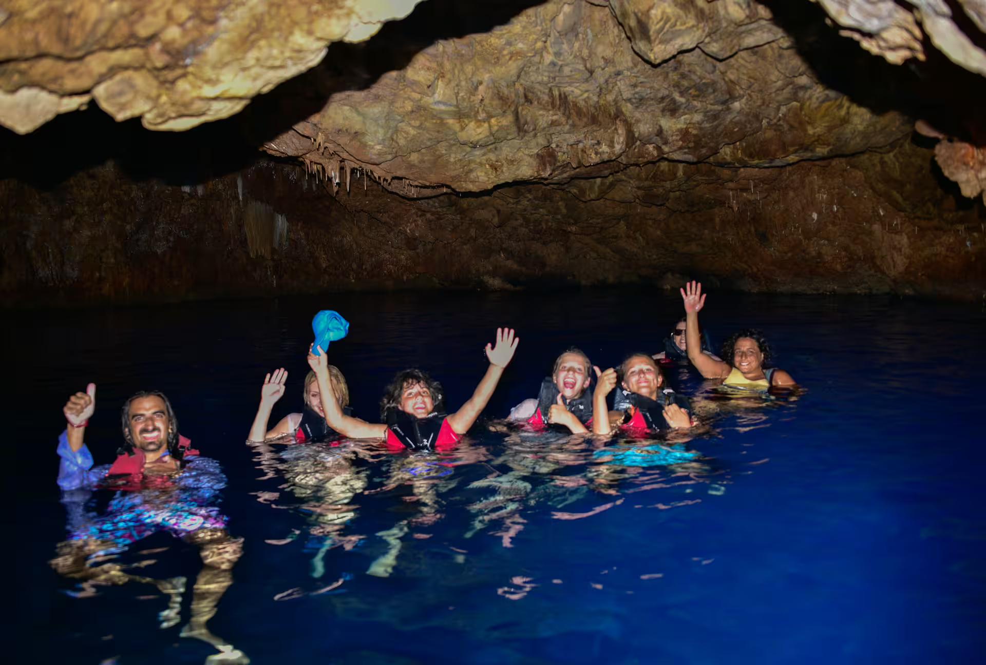 Group swimming in a sea cave during SUP in Kardamyli, Mani Peninsula, wearing life jackets in blue water