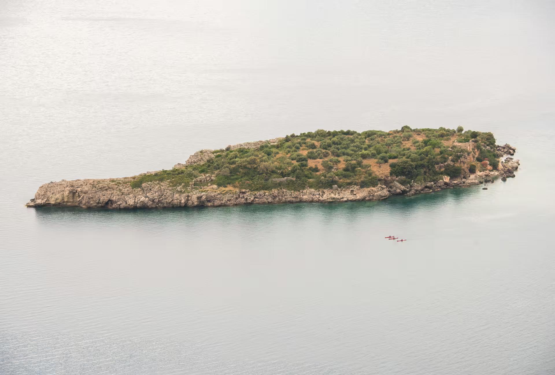 Aerial view of islet near Kardamyli with paddlers on a SUP tour, exploring calm turquoise waters in Mani