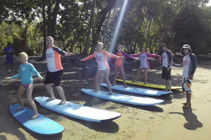 Group of surf students practicing stance on surfboards at Manuel Antonio beach, ideal for family surf lessons.