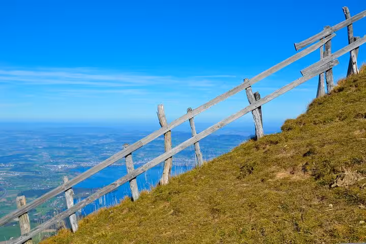 Panoramic view from a Swiss mountain with a rustic wooden fence, showcasing the breathtaking alpine landscape.