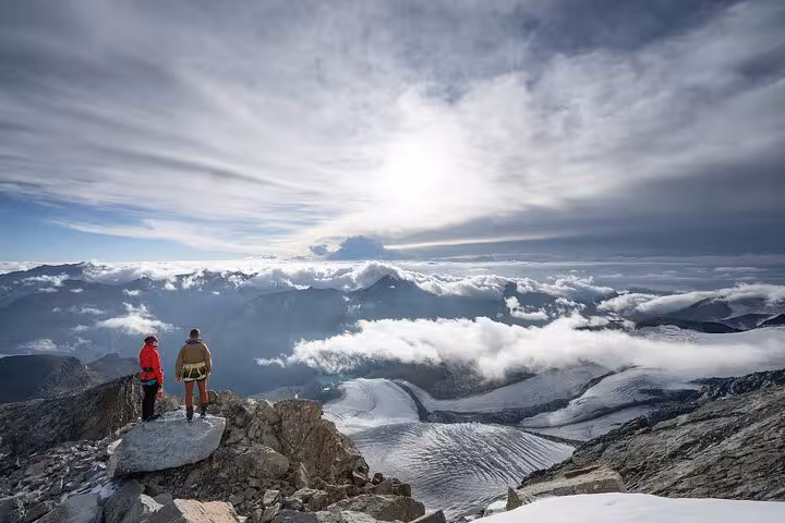 Hikers on a Swiss Alpine ridge above glaciers and clouds on a 4 day trekking tour through the Alps