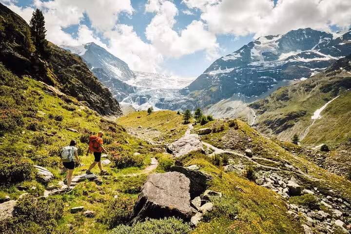Two hikers exploring the stunning Swiss Alps landscape, a highlight of customizable Swiss Travel Pass itineraries.