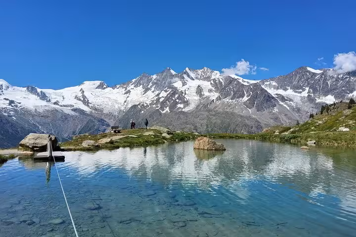 Crystal-clear Swiss mountain lake reflecting snowy peaks on Swiss Magic Through the Alps 4 day trek