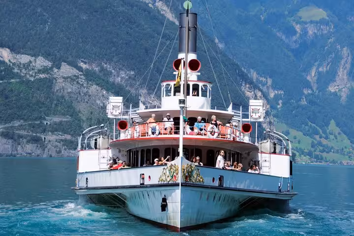 Tourists enjoying a lake cruise on a classic paddle steamer with stunning Swiss Alps backdrop, ideal for scenic tours.