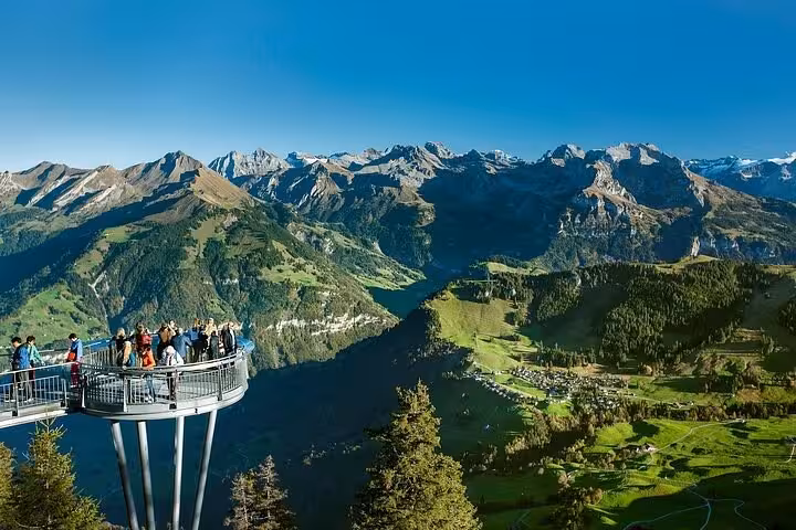 Tourists enjoying breathtaking views of the Swiss Alps from a scenic observation deck on the 3 Mountains tour.