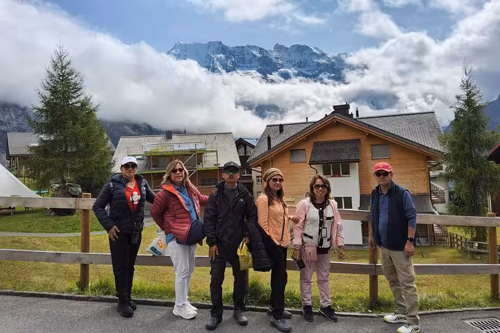 Small group travelers in a Swiss alpine village with Jungfrau mountains and clouds on a 4-day Alps tour