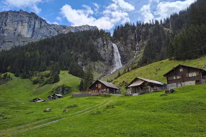 Swiss Alps trekking valley with waterfall and mountain chalets, scenic stop on 4-day Swiss Magic tour