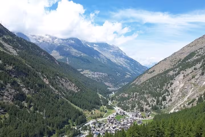 Panoramic Swiss Alps valley with a quaint mountain village, scenic stop on Zurich Airport to Zermatt day trip