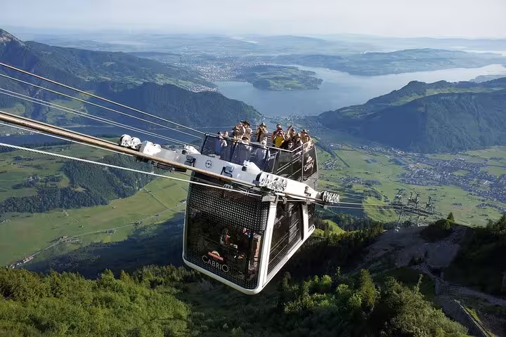 Aerial view of a scenic cable car ride over lush Swiss landscapes and lakes, part of Swiss Travel Pass Tours.