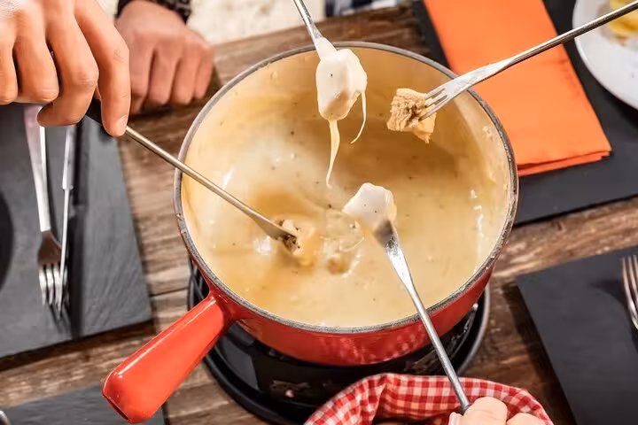 Diners enjoying traditional Swiss cheese fondue, a delicious culinary experience on your Swiss tour.
