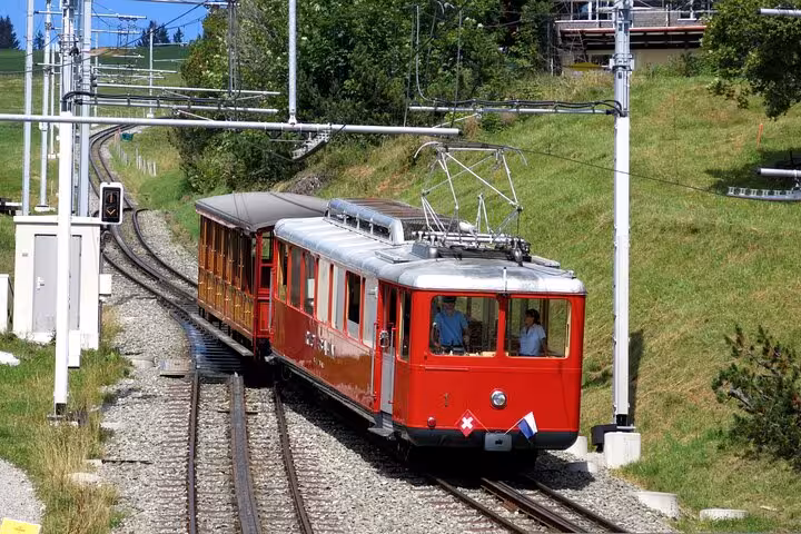 Vintage red Swiss funicular train ascending lush green hills, ideal for exploring Swiss mountain landscapes.